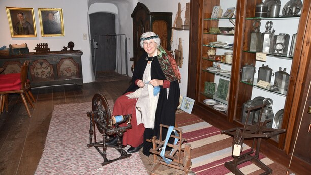 Museumsvermittlerin Gabi Getzner zeigt die ersten Schritte zum eigenen Wollfaden. Spinnkurs in historischer Umgebung